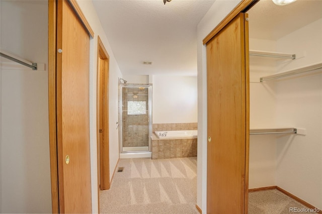 bathroom with a shower stall, a garden tub, a spacious closet, and baseboards