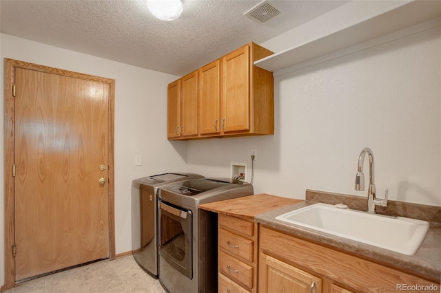 clothes washing area featuring cabinet space, washing machine and clothes dryer, and a textured ceiling