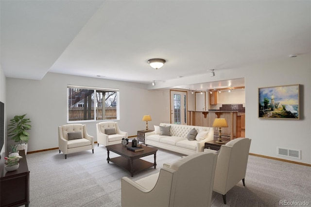 living area with rail lighting, light colored carpet, and baseboards