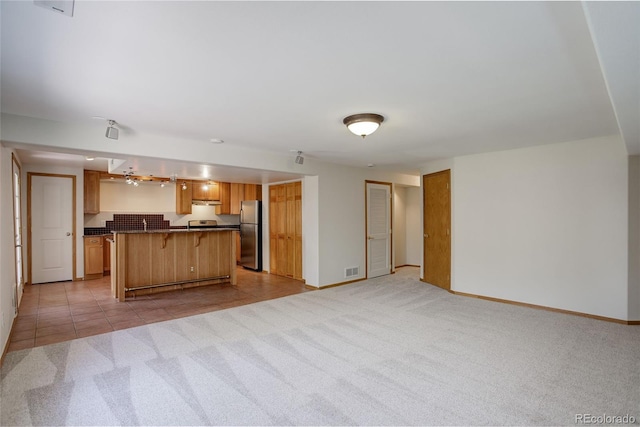 kitchen with freestanding refrigerator, open floor plan, light carpet, and dark countertops