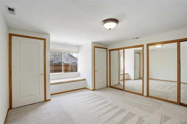 unfurnished bedroom with multiple closets, light colored carpet, and baseboards