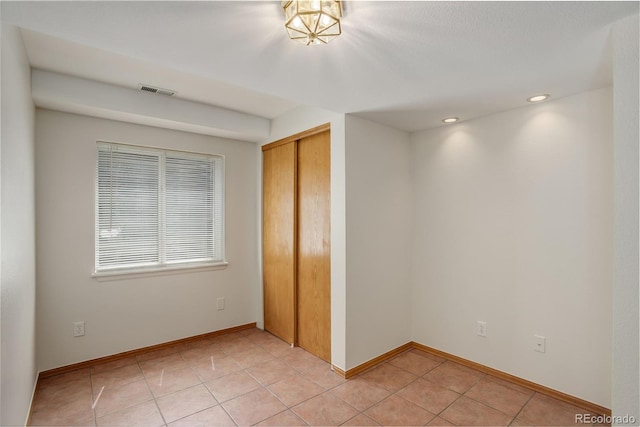 unfurnished bedroom featuring a closet, light tile patterned floors, baseboards, and recessed lighting