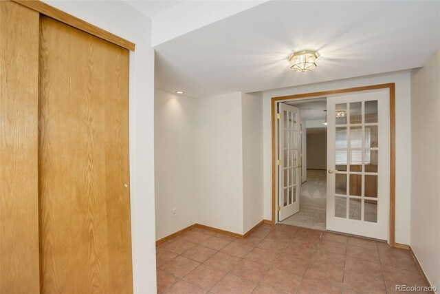 empty room with french doors, light tile patterned floors, and baseboards