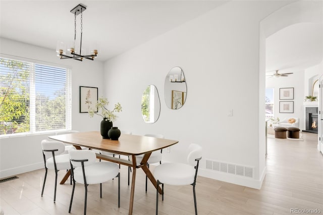 5282 E 116th Ave, Thornton, CO 80233 - dining room with plenty of natural light, a chandelier, a lit fireplace, and light wood-style flooring