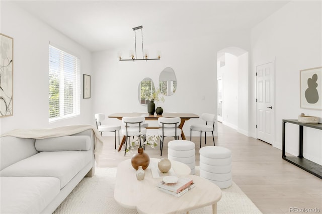 5282 E 116th Ave, Thornton, CO 80233 - living room featuring arched walkways, light wood finished floors, and a chandelier