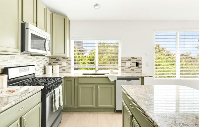 5282 E 116th Ave, Thornton, CO 80233 - kitchen featuring appliances with stainless steel finishes, green cabinets, backsplash, light stone countertops, and light wood-type flooring