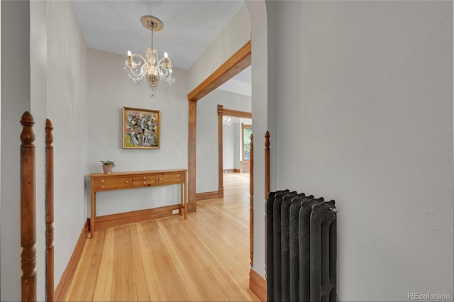 hall with light wood finished floors, radiator heating unit, and baseboards