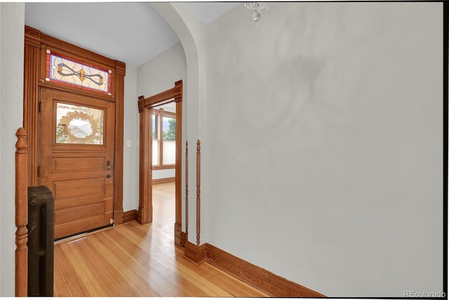 entrance foyer featuring arched walkways, light wood finished floors, and baseboards