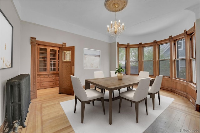 dining area with parquet floors, an inviting chandelier, and radiator heating unit