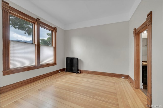 spare room with radiator, baseboards, and wood finished floors