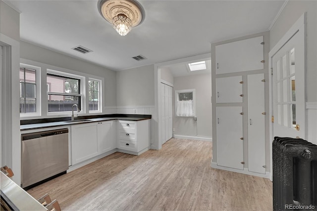 kitchen with a sink, visible vents, light wood-type flooring, and stainless steel dishwasher