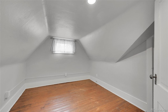 additional living space with baseboards, lofted ceiling, a textured ceiling, and hardwood / wood-style floors