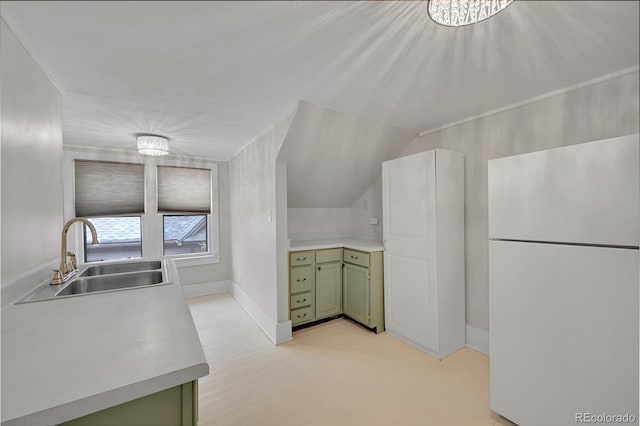 kitchen with a sink, freestanding refrigerator, light countertops, green cabinetry, and vaulted ceiling