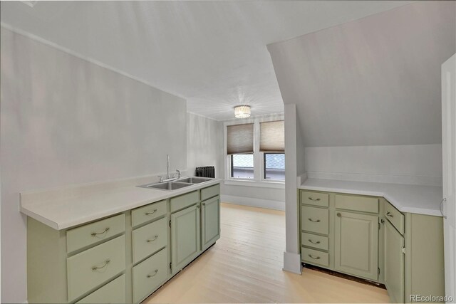 kitchen featuring light wood-type flooring, light countertops, green cabinets, and a sink