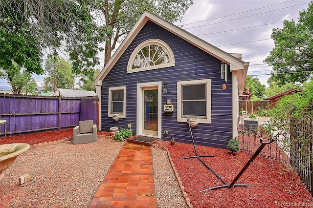 rear view of house with central AC and a fenced backyard