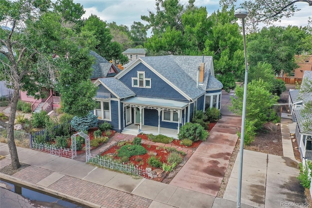 view of front of home featuring a porch, fence, and a shingled roof