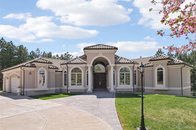 mediterranean / spanish-style home featuring a tiled roof, an attached garage, driveway, and stucco siding