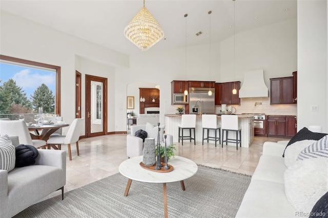 living room featuring light tile patterned floors, arched walkways, a towering ceiling, and a notable chandelier