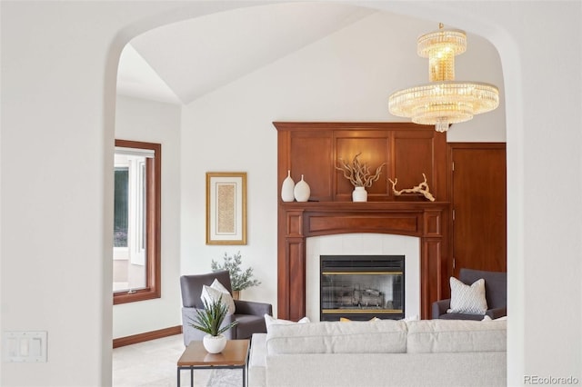 living room with a tiled fireplace, arched walkways, vaulted ceiling, and a chandelier
