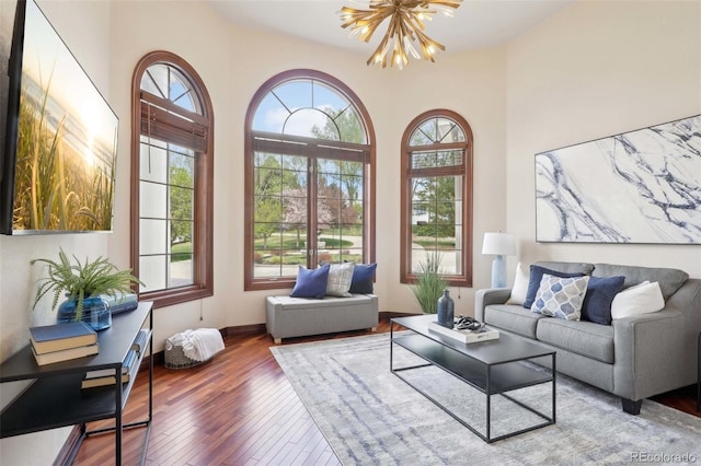 living area with baseboards, a chandelier, and wood finished floors