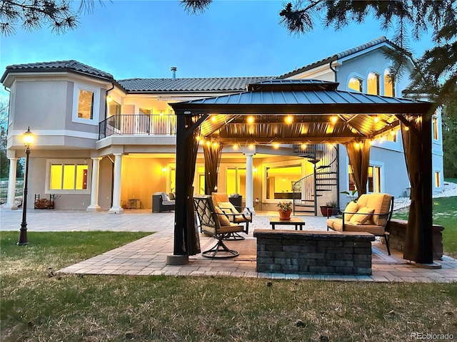 rear view of house with a gazebo, stucco siding, outdoor lounge area, a patio area, and a balcony
