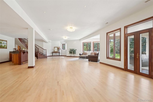 unfurnished living room with visible vents, stairs, baseboards, french doors, and light wood-style flooring