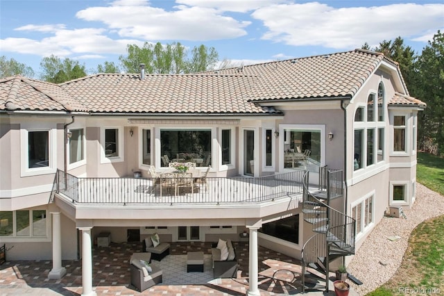 rear view of house with a patio, stucco siding, a tile roof, an outdoor living space, and stairway