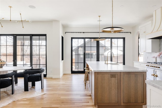 kitchen featuring white cabinets, light wood-style flooring, a kitchen island, light countertops, and a sink