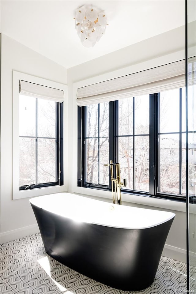 bathroom featuring a freestanding tub, plenty of natural light, and baseboards