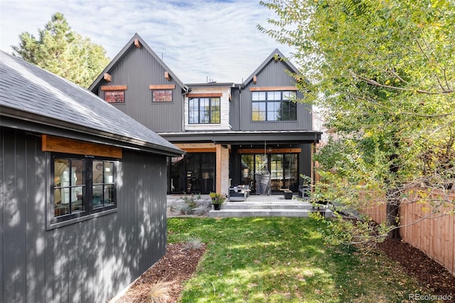 rear view of property with a shingled roof, fence, a lawn, and a patio