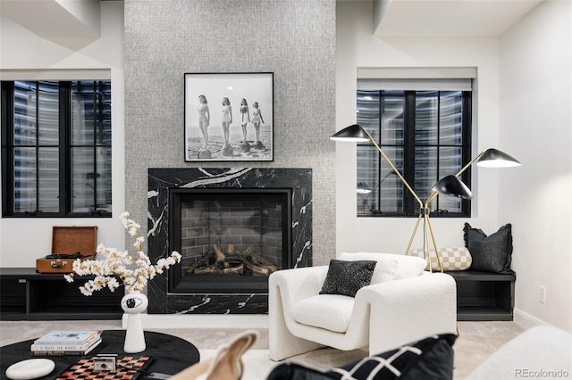 carpeted living room featuring baseboards and a high end fireplace