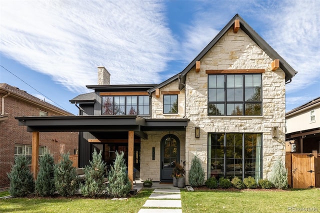 view of front of home with a front yard, stone siding, and a chimney