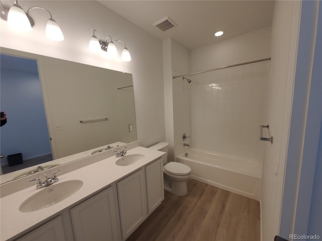 full bathroom with toilet, tiled shower / bath combo, wood-type flooring, and vanity