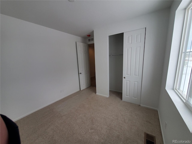 unfurnished bedroom with a closet and light carpet