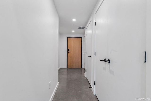 hallway featuring finished concrete flooring, visible vents, baseboards, and recessed lighting
