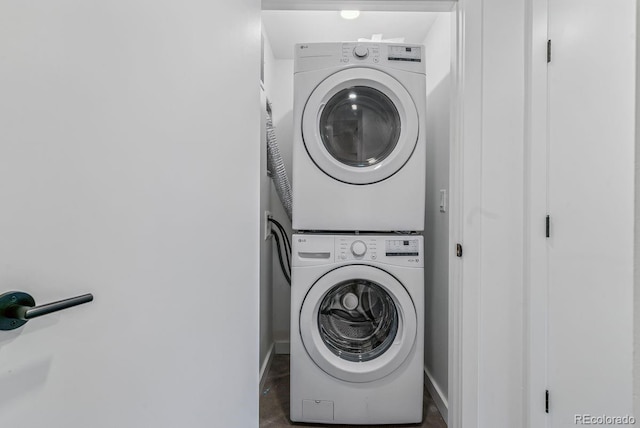 laundry room featuring laundry area, baseboards, and stacked washer / drying machine