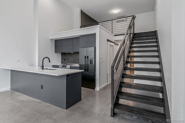 stairway with baseboards, finished concrete flooring, and a high ceiling
