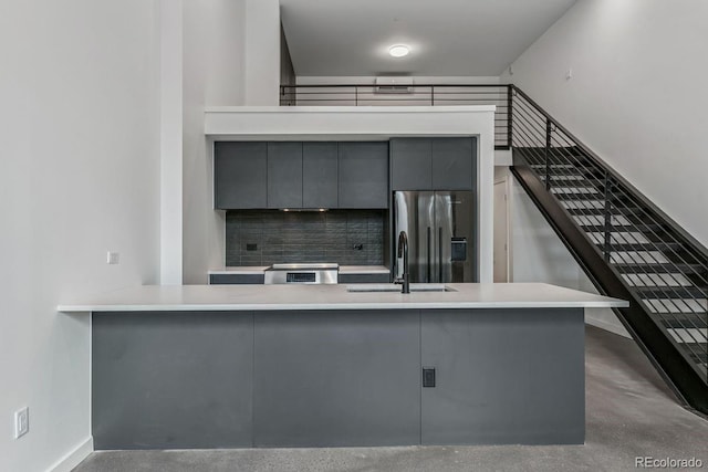 kitchen with a sink, tasteful backsplash, gray cabinets, stainless steel fridge with ice dispenser, and modern cabinets