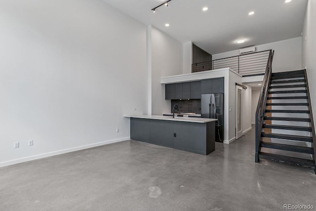 unfurnished living room featuring a sink, stairs, a towering ceiling, baseboards, and concrete floors