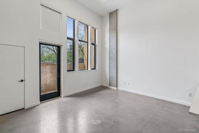 spare room with baseboards and finished concrete flooring