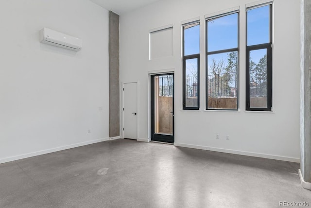 interior space with finished concrete flooring, a wall unit AC, and baseboards
