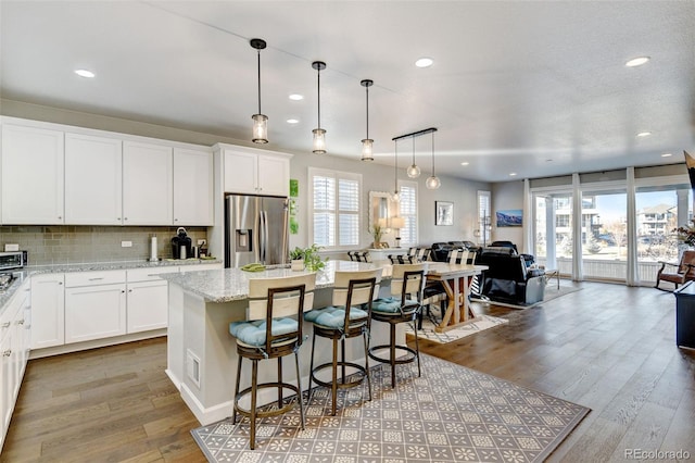 kitchen with a healthy amount of sunlight, a kitchen breakfast bar, a center island, and stainless steel fridge with ice dispenser