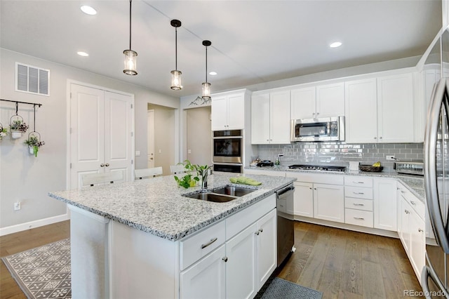 kitchen featuring sink, an island with sink, dark wood-type flooring, appliances with stainless steel finishes, and white cabinets