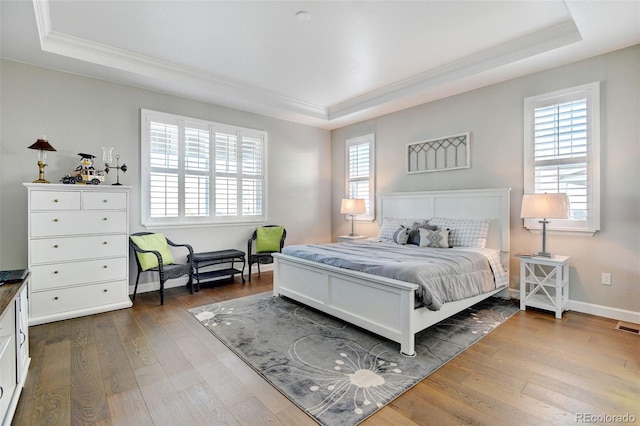 bedroom with ornamental molding, a raised ceiling, and dark hardwood / wood-style floors