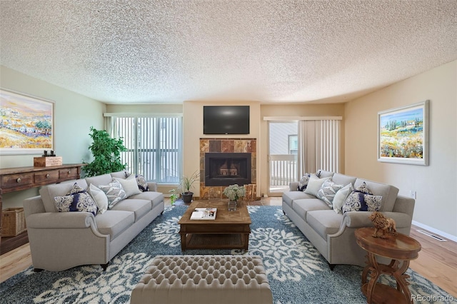 living area featuring a tile fireplace, wood finished floors, and a textured ceiling