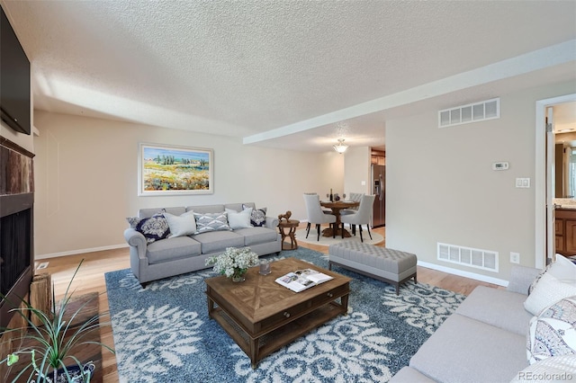 living area featuring light wood finished floors, baseboards, a textured ceiling, and a fireplace