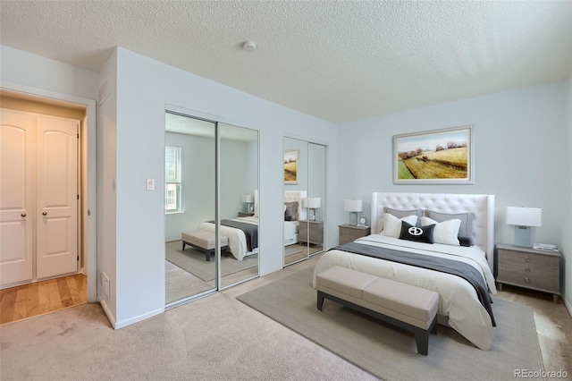 carpeted bedroom featuring two closets and a textured ceiling