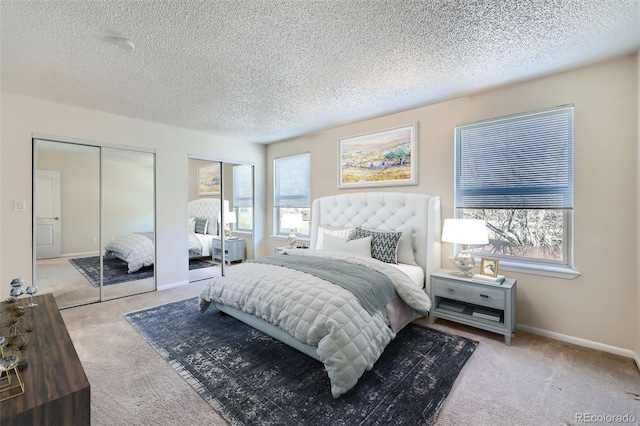 bedroom with carpet flooring, multiple closets, a textured ceiling, and baseboards