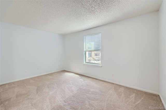 spare room featuring carpet floors, baseboards, and a textured ceiling