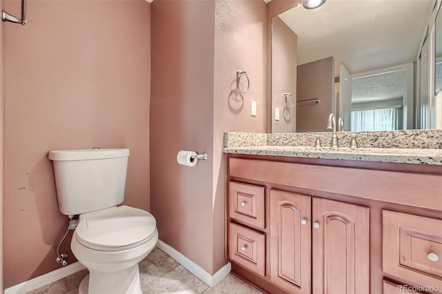 bathroom with baseboards, toilet, and vanity